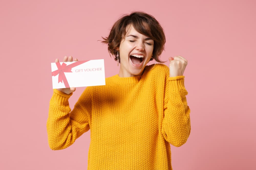 Excited woman holding a gift voucher, representing Director’s Cut Hairdressing, Nails & Beauty in Crystal Peaks, Sheffield.