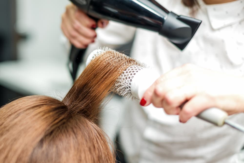 Professional hairdresser blow-drying and styling hair with a round brush at Director’s Cut in Crystal Peaks, Sheffield.