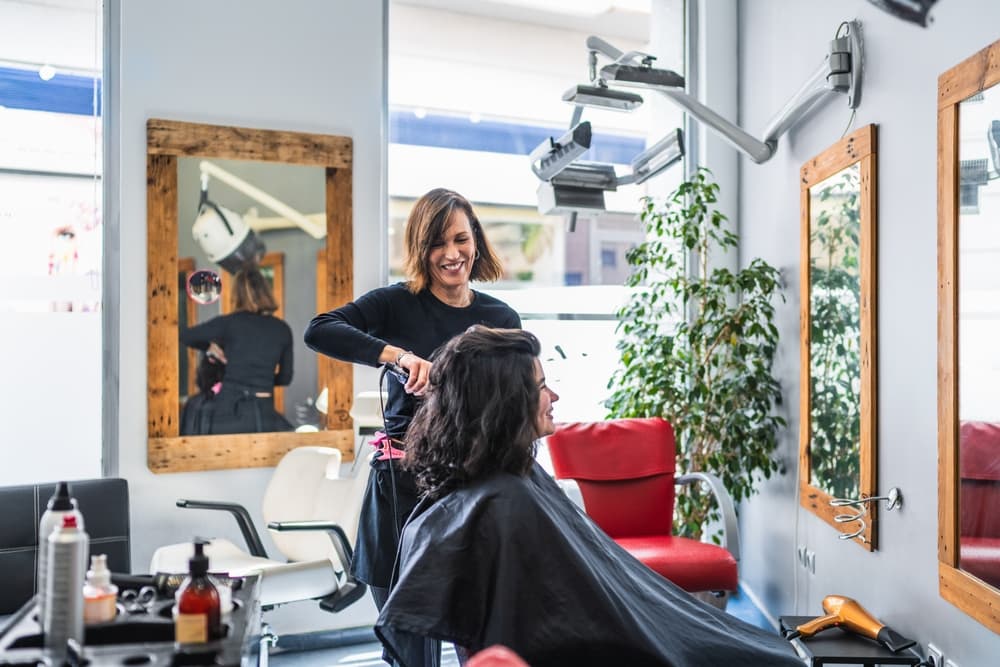 Hair stylist cutting a client’s hair in the bright, modern salon at Director’s Cut Hairdressing, Nails & Beauty in Crystal Peaks, Sheffield.